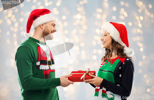 Image of happy couple in sweaters with christmas gift