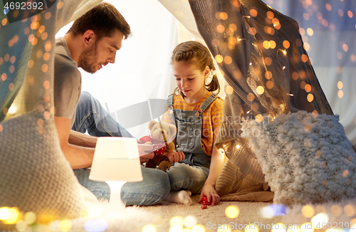 Image of happy family playing with toy in kids tent at home