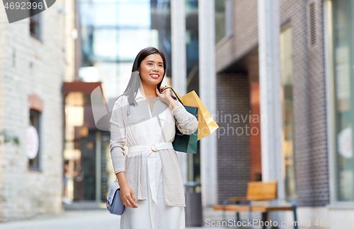 Image of asian woman with shopping bags walking in city