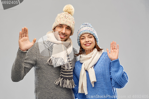 Image of happy couple in winter clothes waving hands