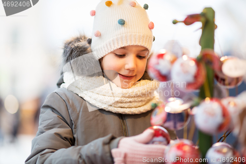 Image of little girl choosing christmas balls at market