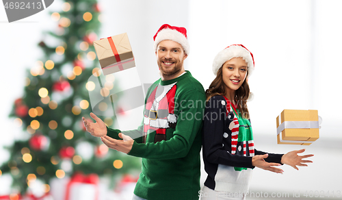 Image of happy couple in sweaters with christmas gifts