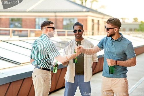 Image of happy male friends drinking beer at rooftop party