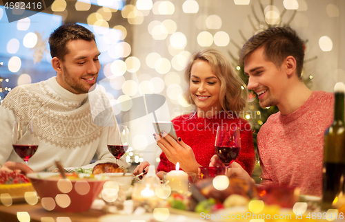 Image of friends with cellphone celebrate christmas at home
