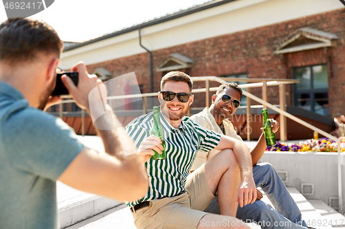 Image of man photographing friends drinking beer on street