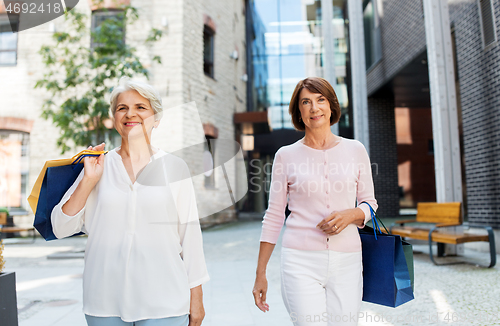 Image of senior women with shopping bags walking in city