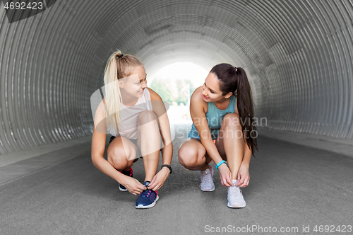 Image of sporty women or female friends tying shoe laces