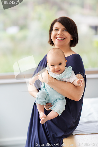 Image of middle-aged mother holding baby daughter at home