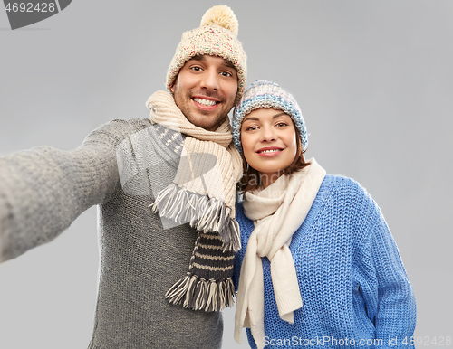 Image of happy couple in winter clothes taking selfie