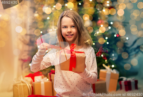 Image of smiling girl with christmas gift at home