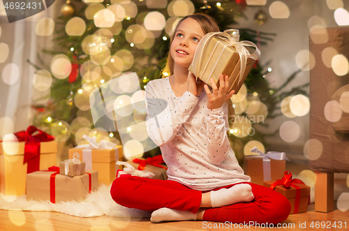 Image of smiling girl with christmas gift at home