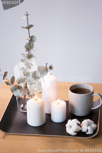 Image of candles, tea and branches of eucalyptus on table