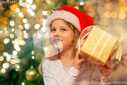 Image of smiling girl in santa hat with christmas gift