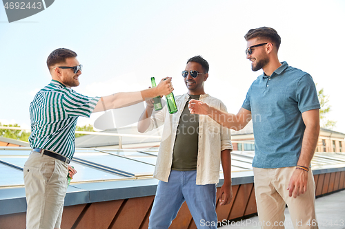 Image of happy male friends drinking beer at rooftop party