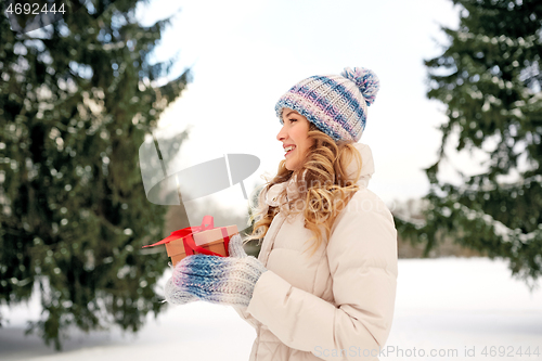 Image of happy young woman with christmas gift in winter