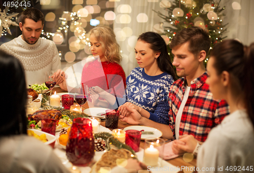 Image of friends having home christmas dinner and praying