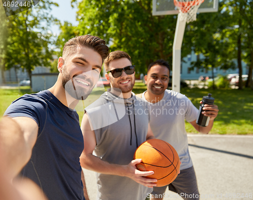 Image of happy men taking selfie on basketball playground