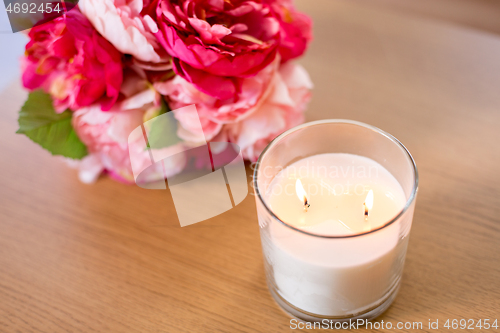 Image of burning fragrance candle and flower bunch on table