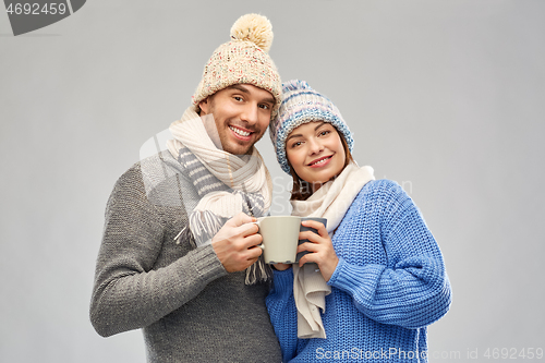 Image of happy couple in winter clothes with mugs