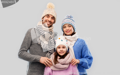 Image of happy family in winter clothes on grey background