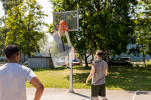 Image of group of male friends playing street basketball