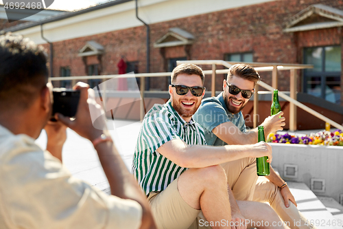 Image of man photographing friends drinking beer on street