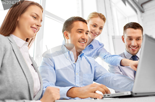 Image of happy business team with laptop computer in office