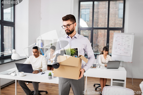 Image of sad fired male office worker with personal stuff