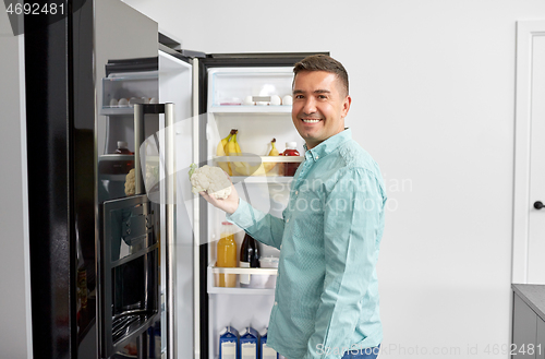 Image of man taking vegetable from fridge at home kitchen