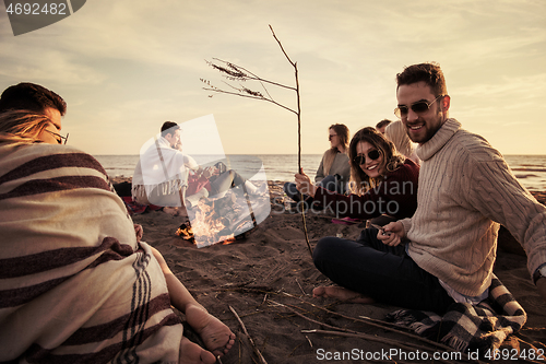 Image of Couple enjoying with friends at sunset on the beach