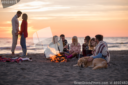 Image of Couple enjoying with friends at sunset on the beach