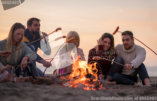 Image of Group Of Young Friends Sitting By The Fire at beach