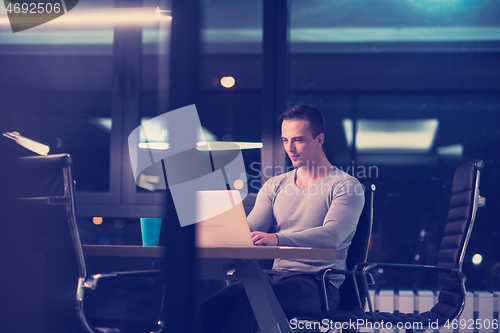 Image of man working on laptop in dark office