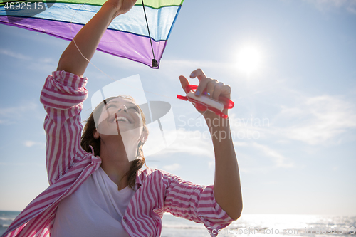 Image of Young Woman with kite at beach on autumn day