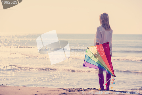 Image of Young Woman with kite at beach on autumn day