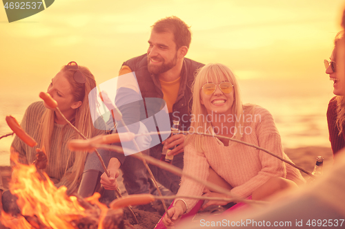 Image of Group Of Young Friends Sitting By The Fire at beach