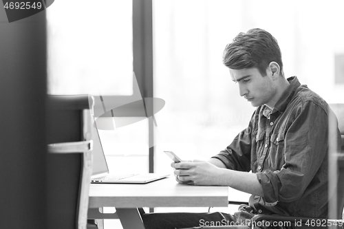 Image of Young casual businessman using smartphone