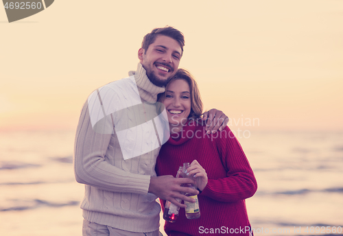 Image of Couple hugging and drinking beer together at the beach