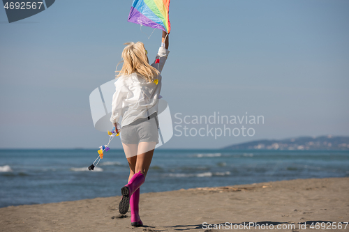 Image of Young Woman with kite at beach on autumn day