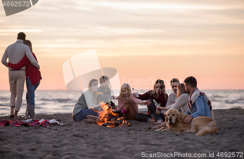 Image of Couple enjoying with friends at sunset on the beach