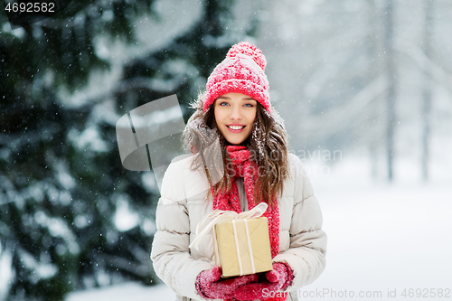 Image of happy young woman with christmas gift in winter