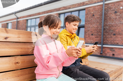 Image of children with smartphones sitting on street bench