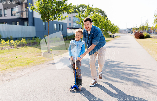 Image of happy father and little son riding scooter in city