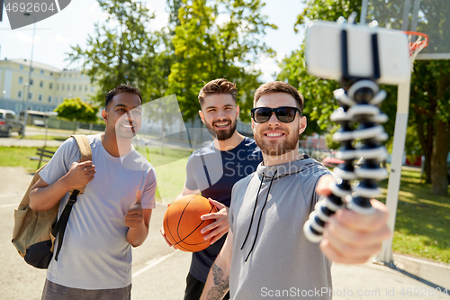 Image of happy men taking selfie on basketball playground