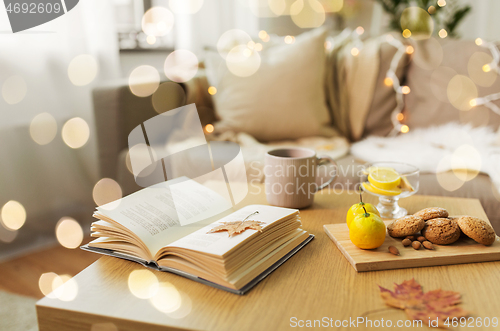 Image of book, lemon, tea and cookies on table at home