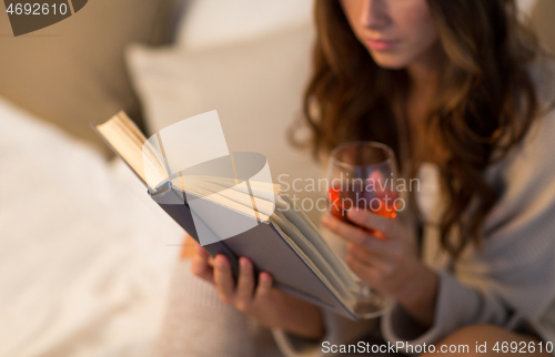 Image of close up of woman reading book and drinking wine