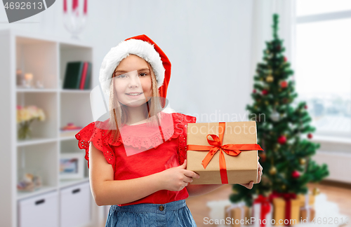 Image of girl in santa hat with christmas gift at home