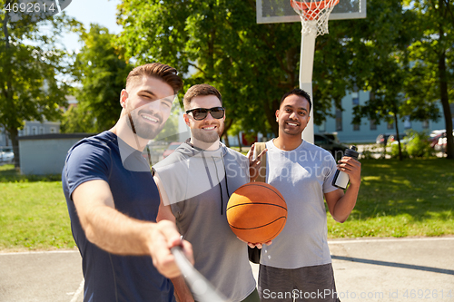 Image of happy men taking selfie on basketball playground