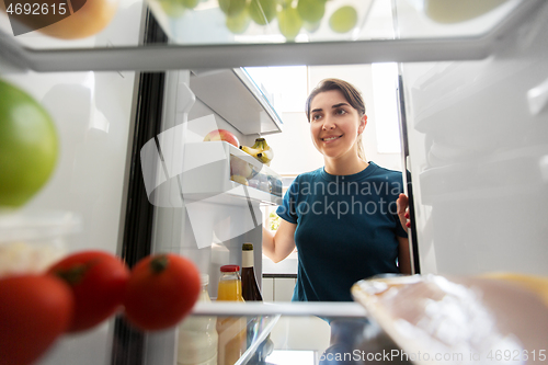 Image of happy woman at open fridge at home kitchen