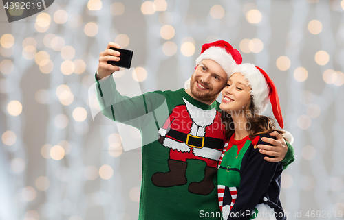 Image of happy couple in christmas sweaters taking selfie